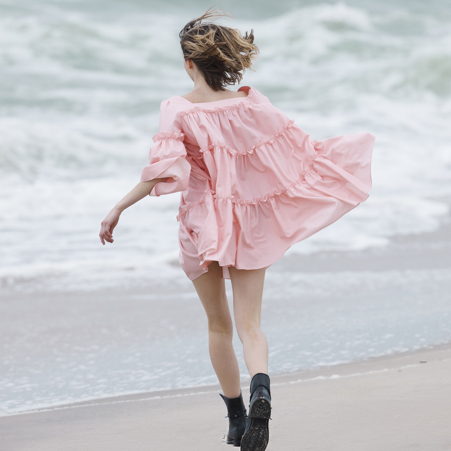 Tiered pink dress in motion on the shoreline